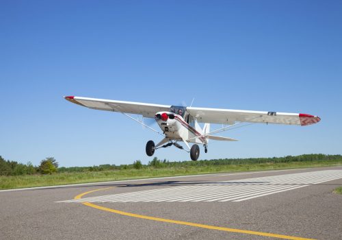 Small white single engine airplane takes off from a municipal airfield in rural Minnesota